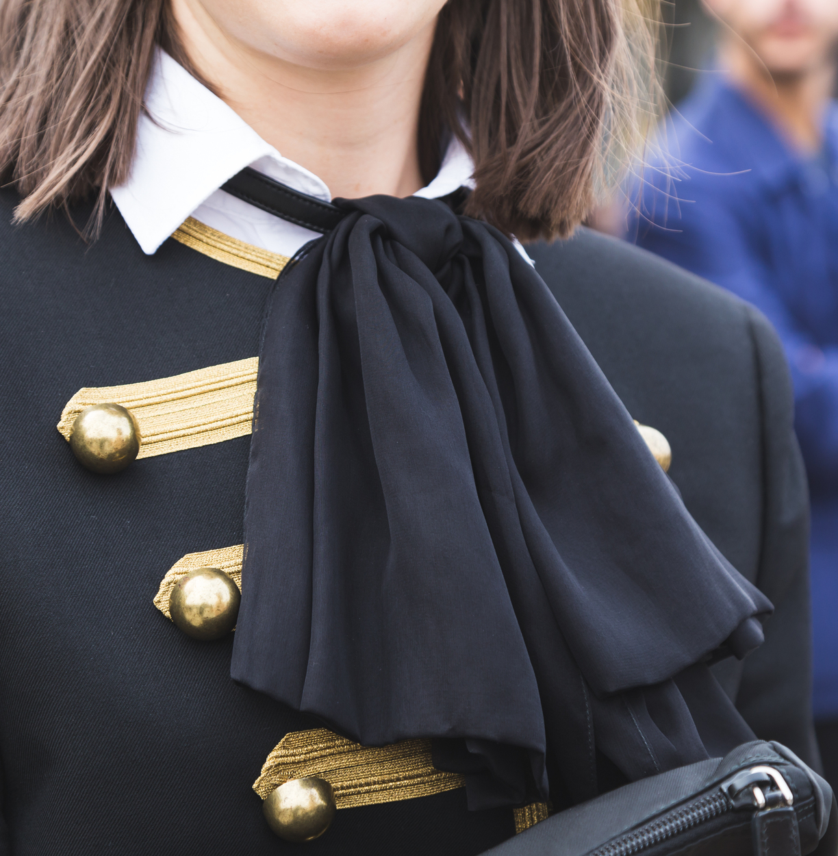Close-up of a military-inspired blazer with gold trim and oversized bow detail